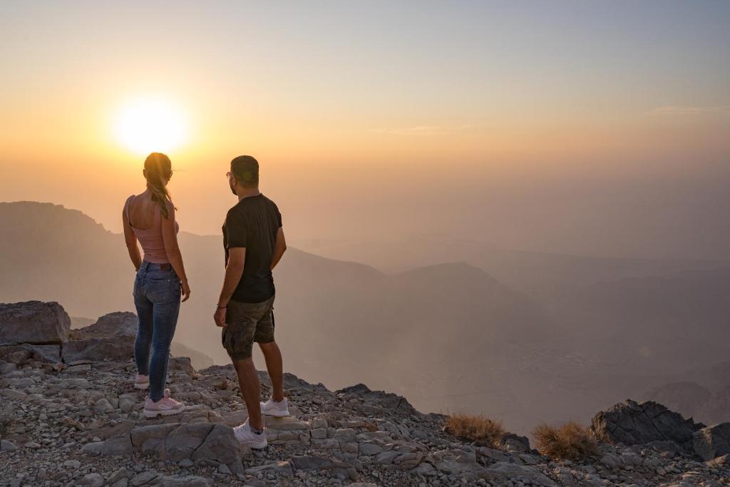 Pāris vēro saulrietu kalnos pie The Cove Rotana Resort