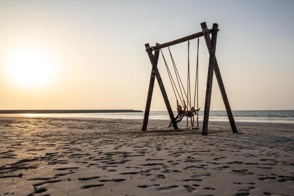 Šūpoles pludmalē pie The Cove Rotana Resort saulrietā