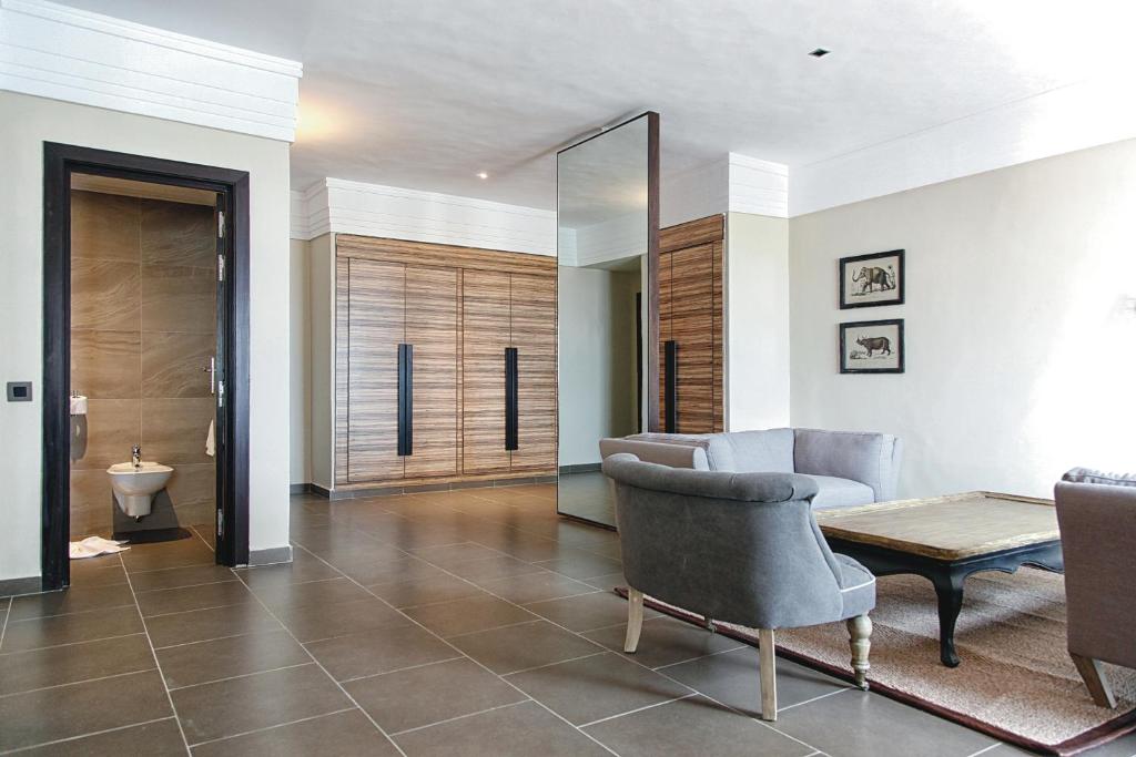 Mūsdienīgs viesnīcas numurs ar stilīgu dizainu, kas ietver ērtus krēslus un koka galdu. Apskatāma arī vannas istaba un liela drēbju skapis.