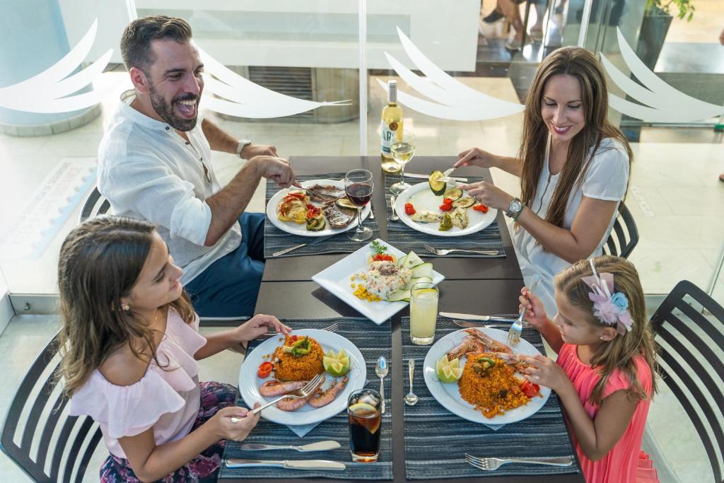 Ģimenes vakariņas restorānā ar daudziem dažādiem ēdieniem un dzērieniem, kur visi izskatās priecīgi un bauda laiku kopā.
