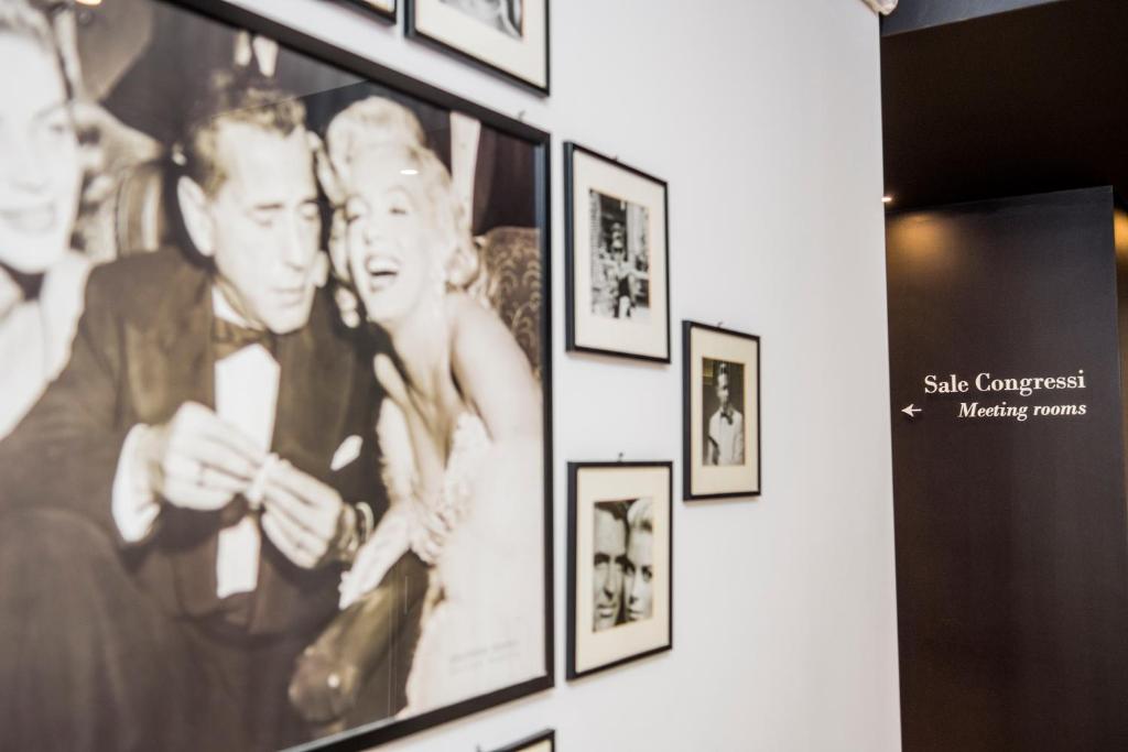 Sienas dekorācija ar melnbaltām fotogrāfijām, kas attēlo slavenus cilvēkus, un norāde uz sanāksmju telpām.