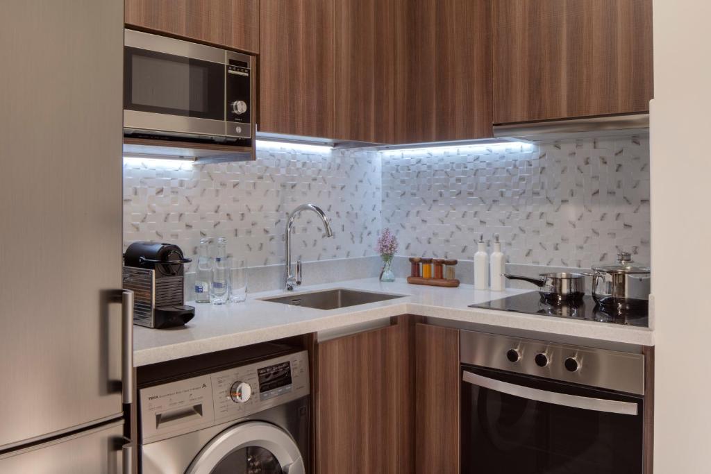 Mūsdienīga virtuve ar koka apdari, mikroviļņu krāsni, kafijas aparātu un traukiem. Gaismas akcenti un eleganta dizaina detaļas, kas rada siltu atmosfēru.