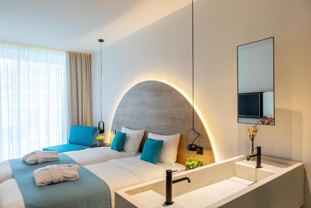 Mūsdienīga viesnīcas numura iekārtojums ar divām gultām, komfortablu dīvānu un stilīgu apgaismojumu. Numurā ir arī moderns izlietnes dizains un lieli logi, kas nodrošina daudz gaismas.