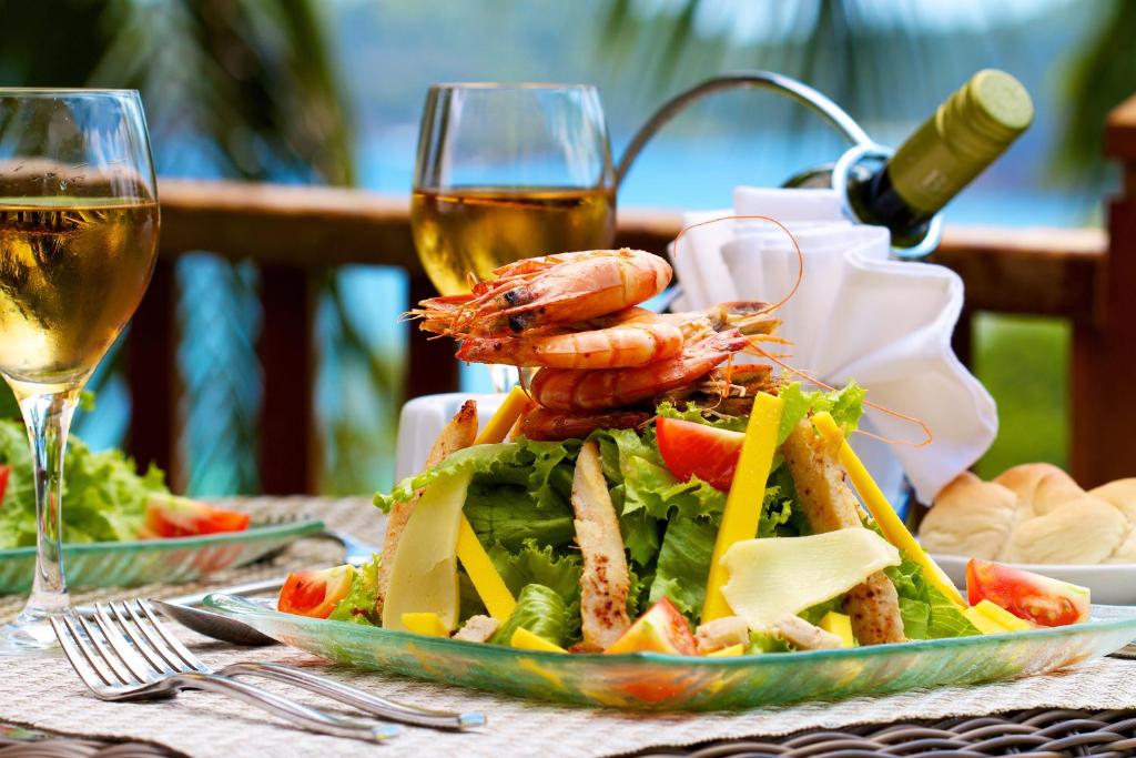 Svaiga jūras velšu salātu plate ar garnelēm, dārzeņiem un glāzi baltvīna, baudot ēdienu brīvā gaisotnē.