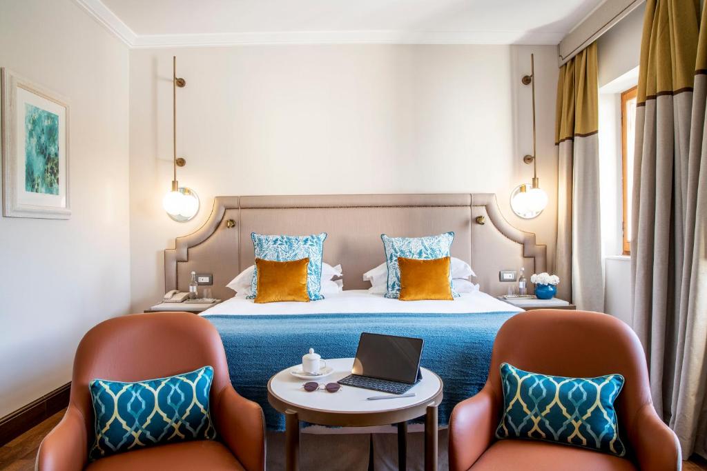 Moderns viesnīcas numurs ar stilīgu iekārtojumu, izceļot gaišas krāsas un komfortablas mēbeles. Numurā ir divas krēsli un galds, kā arī ērtā gulta ar dekoratīvām spilveniem.