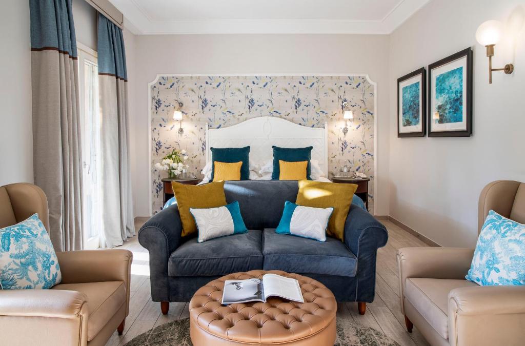 Elegants viesistabas interjers ar ziedu motīviem uz sienas, mīkstiem dīvāniem un krēsliem, kā arī mūsdienīgu apgaismojumu. Siltas krāsas un dekoratīvi spilveni rada mājīgu atmosfēru.