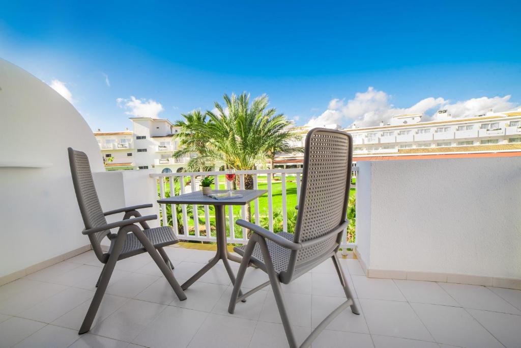 Balkons ar divām krēslām un galdu, redzams zaļš dārzs un zils debesis. Ideāla vieta relaksācijai un atpūtai.