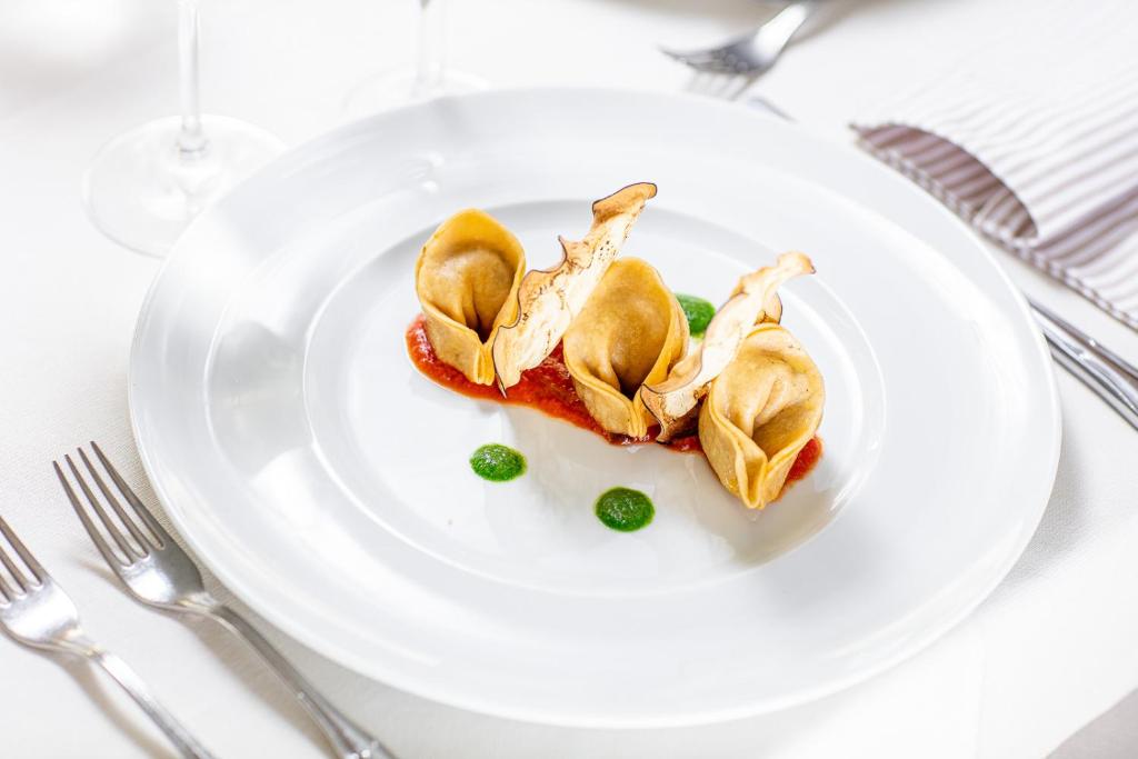 Gards un elegants ēdiens, kas sastāv no trīs izsmalcinātām mantiņām uz tomātu mērces ar zaļo piedevu. Ideāls piemērs modernai kulinārijai.