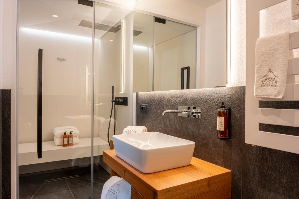 Mūsdienīgs vannas istabas interjers ar stikla dušu, elegantu izlietni uz koka plaukta un stilīgām vannas piederumiem. Ideāla izvēle modernām mājām.