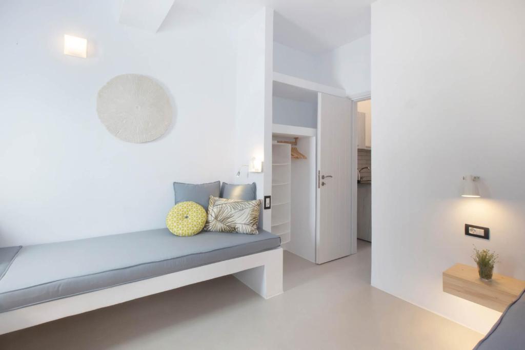 Moderns, gaišs interjers ar ērtu dīvānu, dekoratīviem spilveniem un praktisku skapīti. Telpā ir minimālistisks dizains ar baltām sienām un dabīgiem elementiem.