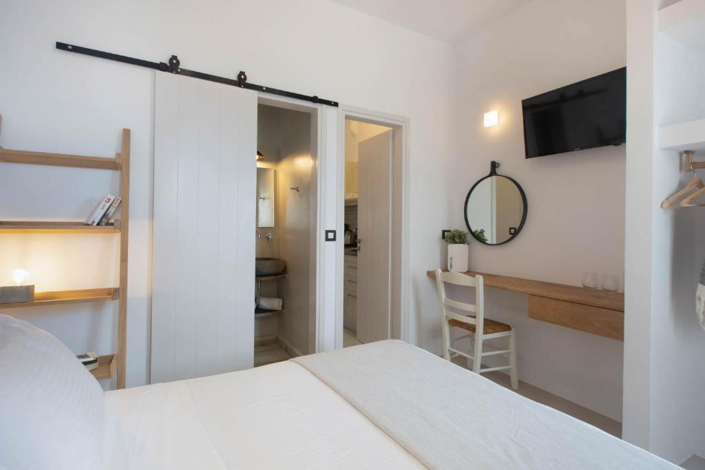 Mūsdienīga guļamistaba ar baltām sienām, koka plauktu un rakstāmgalds, kurā ir spogulis un televizors. Ieeja vannas istabā ir caur slīdošām durvīm.