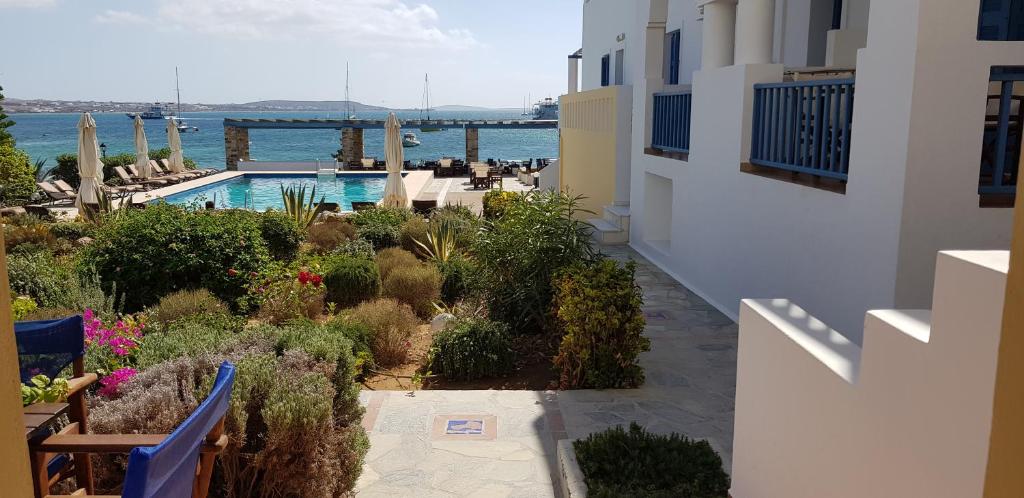 Vasaras kūrorts ar skatu uz peldbaseinu un jūru, ko ieskauj zaļumi un ziedi. Relaxējoša atmosfēra, kas aicina uz atpūtu.