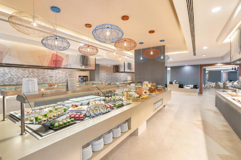 Moderns bufetes restorāns ar plašu ēdienu izvēli un stilīgām, gaisīgām lampām. Interjers ir gaišs un elegants, radot patīkamu atmosfēru.