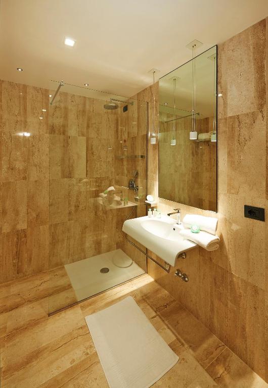 Mūsdienīga vannas istaba Cala Cuncheddi viesnīcā ar dabīgiem akmens elementiem.