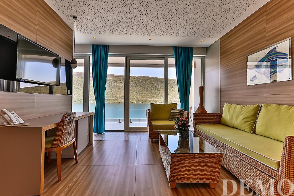 Mūsdienīgs viesnīcas numurs ar plašu logu un skaistu skatu uz dabu. Interjers ir elegants, ar zaļām mēbelēm un koka akcentiem.