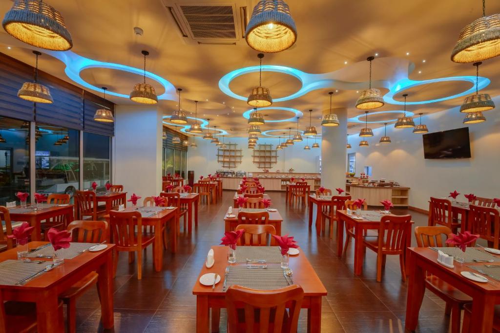 Mūsdienīgs restorāns ar elegantiem koka galdiem un sarkaniem salvetēm, izgaismots ar stilīgām lampām un modernu apgaismojumu. Pateicoties plašajiem logiem, telpā valda gaiša un patīkama atmosfēra.