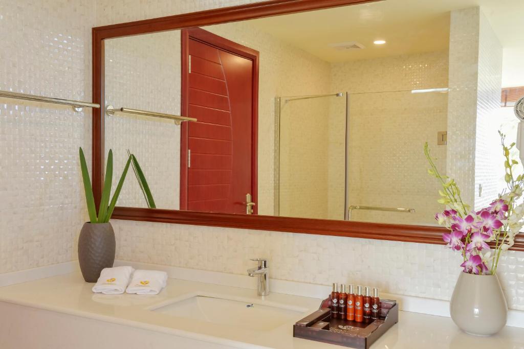 Mūsdienīgs un elegants vannas istabas interjers ar spoguli, krāsaino durvju un dekoratīvām augu kompozīcijām. Vannas istabā ir saskaņoti dvieļi un augstas kvalitātes kosmētikas komplekts.