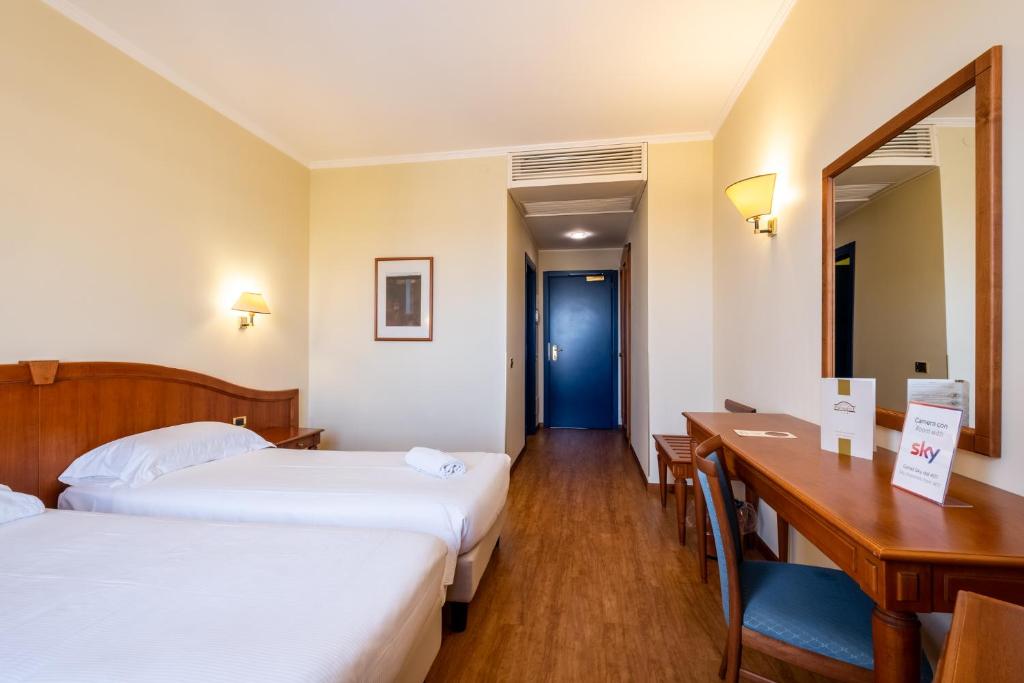 Mūsdienīgs viesnīcas numurs ar divām atsevišķām gultām, koka mēbelēm un rakstāmgaldu, kas nodrošina komfortablu vidi atpūtai. Gaiši toņi un ērti apgaismojumi rada patīkamu atmosfēru.