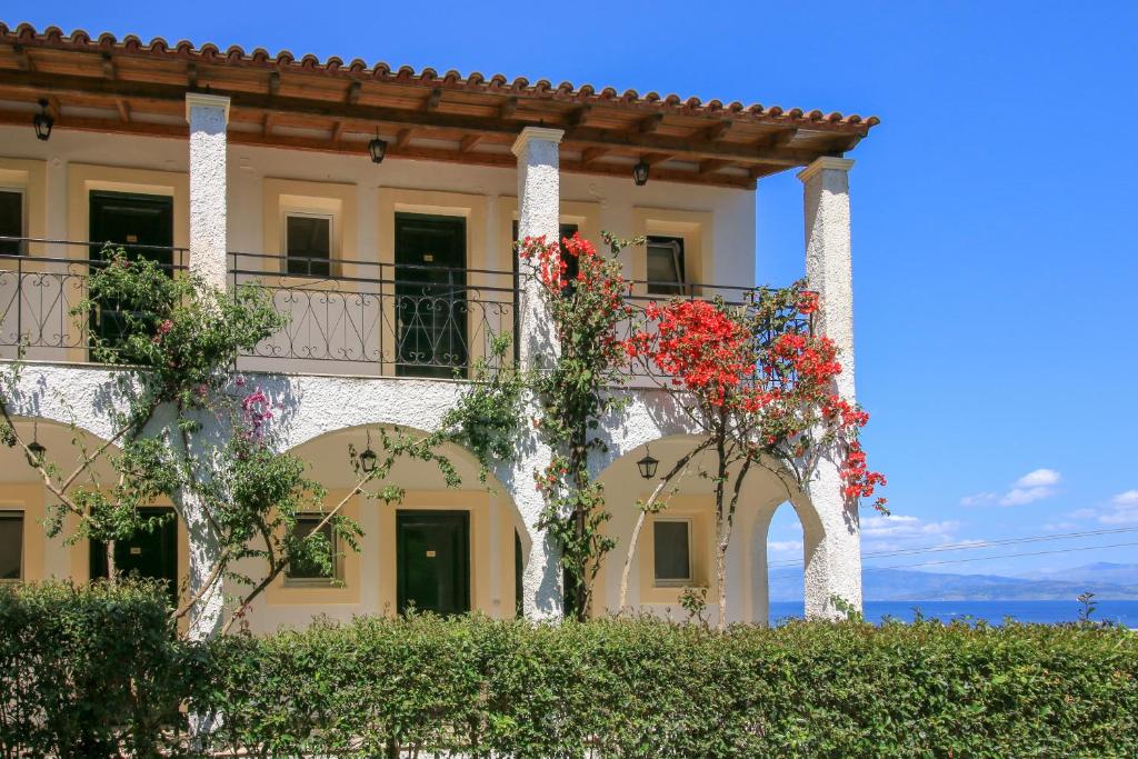 Mūsdienīgs viesu nams ar balkonu, apstādīts ar ziedošām vīnogulājām un skatu uz jūru. Saulains laiks un skaidrs debesis piešķir dzīvīgumu ainai.