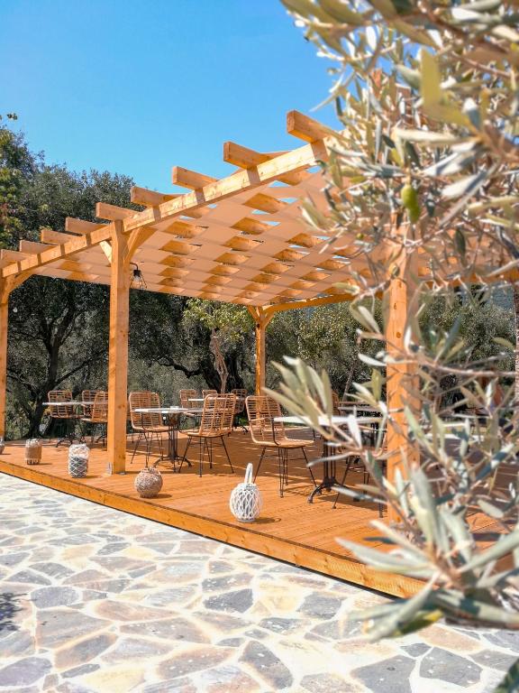 Mūsdienīga koka terase ar ērtām krēslām un galdiem, izvietota starp olīvkokiem, radot patīkamu un relaksējošu atmosfēru. Terasei ir pārklājums, kas nodrošina ēnu saulainās dienās.