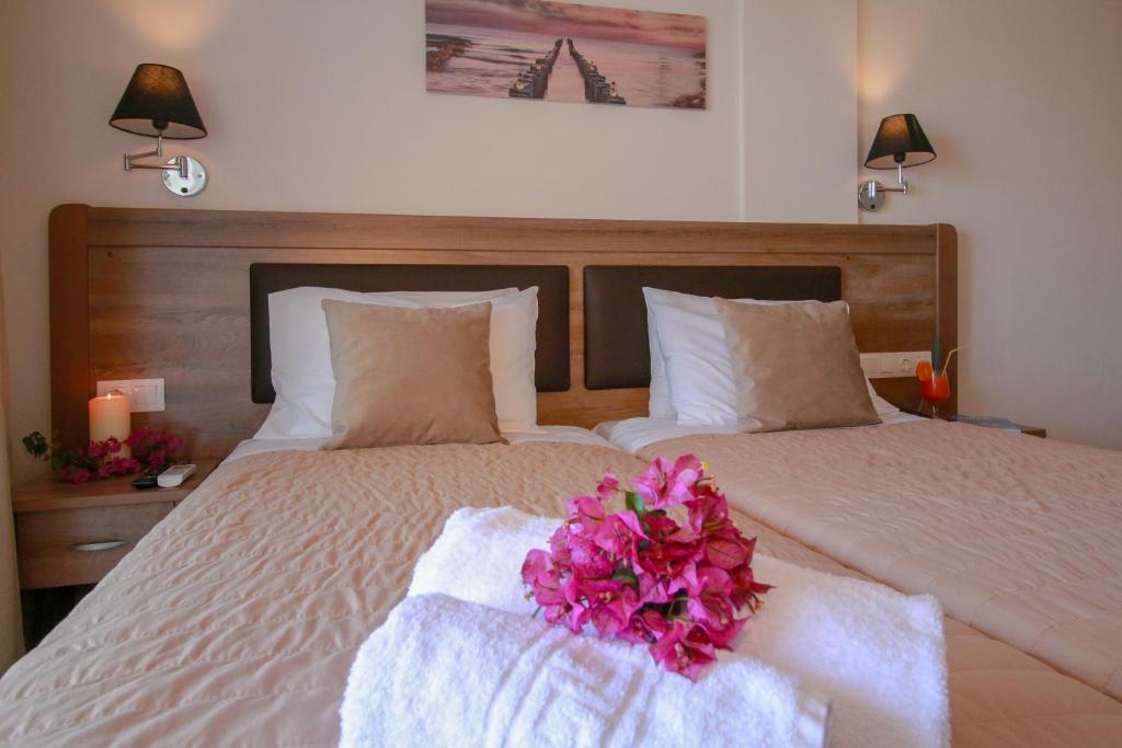 Mūsdienīgs viesnīcas numurs ar divām gultām, dekora elementiem un ziedu kompozīciju uz gultas. Sienā ir gaismas avots un gleznaina ainava.