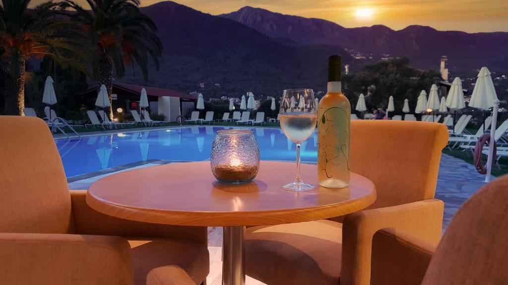 Romantiska skats uz baseinu ar vīna pudeli un glāzi, ideāla atmosfēra atpūtai. Saulrieta gaismas piepilda ainu ar mierīgu noskaņu.