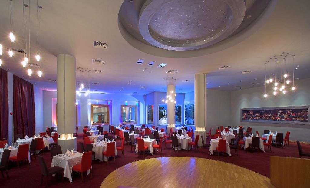 Elegants restorāns ar modernu interjeru, kurā ir daudzas galdiņu kompozīcijas un mūsdienīgas lampas. Telpā ir siltas krāsas un mājīga atmosfēra, ideāli piemērota svinībām un romantiskām vakariņām.
