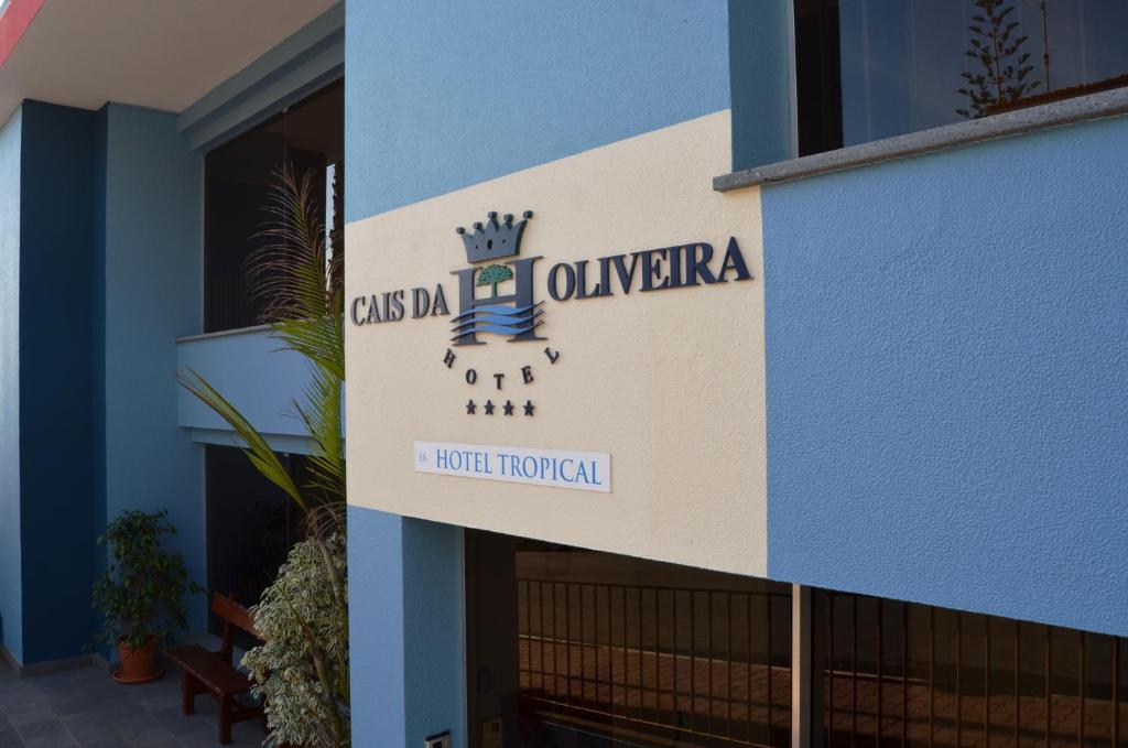 Viesnīcas "Cais da Oliveira" zīme ar pieciem zvaigznēm un tropisko viesnīcu nosaukumu. Moderns un krāsains arhitektūras dizains.