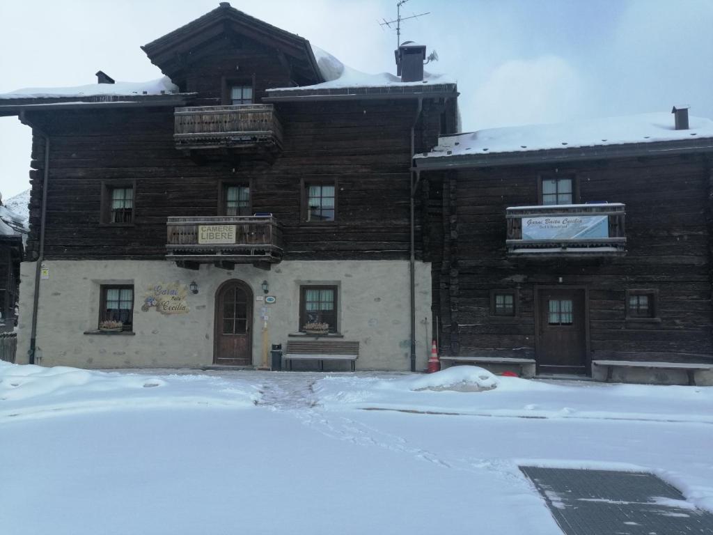 Kalnu viesnīca ar koka fasādi, kas atrodas sniegotā ainavā. Viesnīcas priekšpusē redzams "Cameres Libere" uzraksts un balkoni.