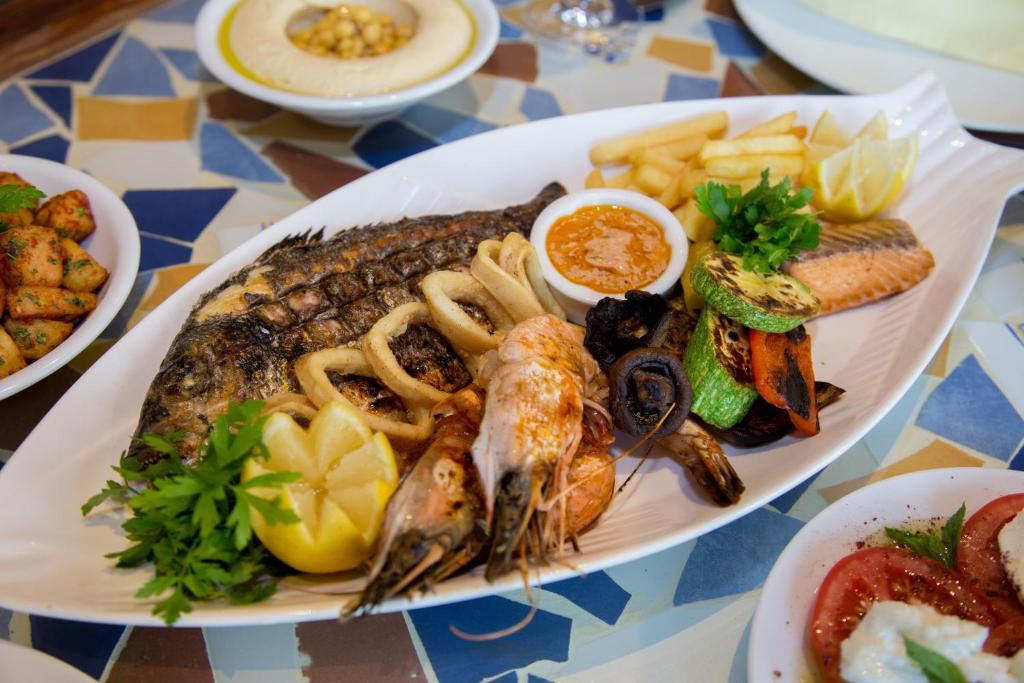 Svaigu jūras velšu šķīvis ar ceptu zivi, garnelēm, kalmāriem un dārzeņiem, pasniegts ar citronu un mērci. Ideāls ēdiens jūras velšu cienītājiem.