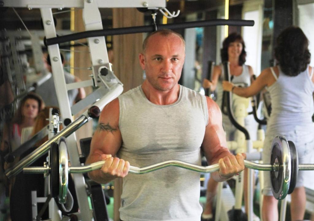 Vīrietis vingro Camyuva Beach Hotel sporta zālē, pacelot svarus.