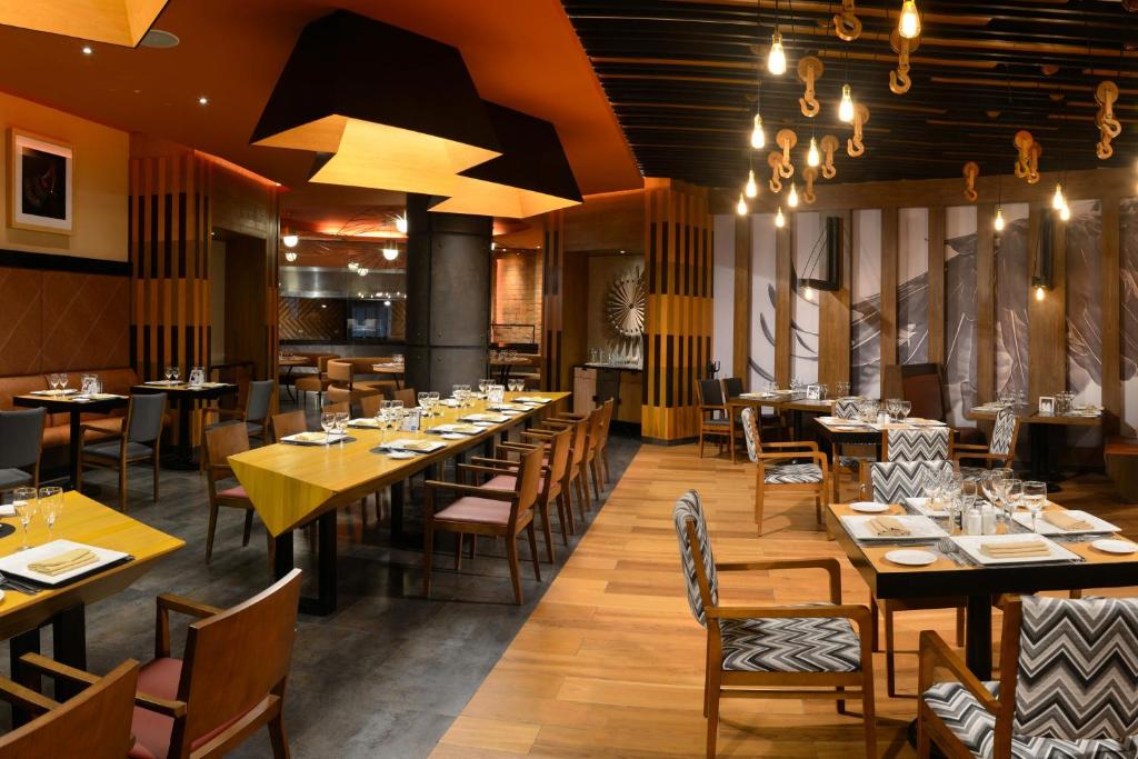 Mūsdienīgs restorāns ar elegantu interjeru, kurā ir izsmalcināti galdi un krēsli, radot patīkamu atmosfēru. Gaisma un moderni akcenti piešķir telpai īpašu šarmu.