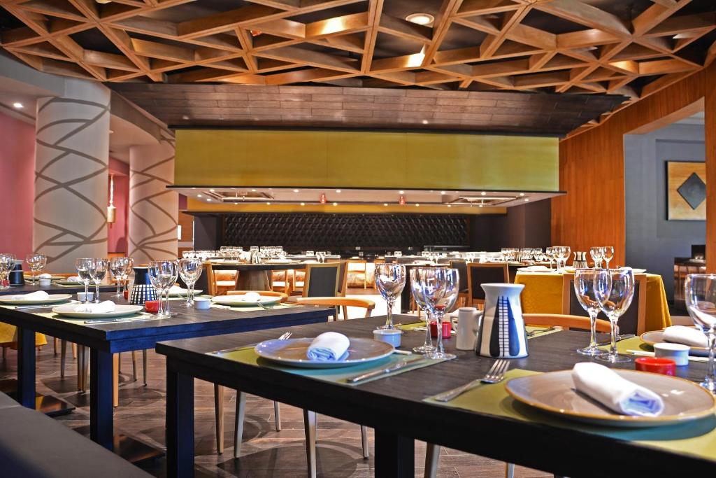 Mūsdienīgs restorāns ar elegantām galdiem, kas klāti ar traukiem un glāzēm, piedāvā viesiem patīkamu atmosfēru. Koka griestu dizains un moderns interjers rada siltu un pievilcīgu vidi.