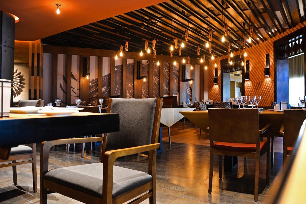 Mūsdienīga restorāna interjers ar siltu apgaismojumu un elegantiem galds un krēsli, radot patīkamu atmosfēru. Vairāki galdi ir sagatavoti viesiem, atspoguļojot modernu dizainu.