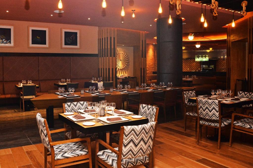 Mūsdienīgs restorāns ar elegantu interjeru, kurā ir koka grīdas un stilīgas ēdamzāles mēbeles. Gaismas elementi rada siltu atmosfēru, kas aicina apmeklētājus baudīt maltīti.