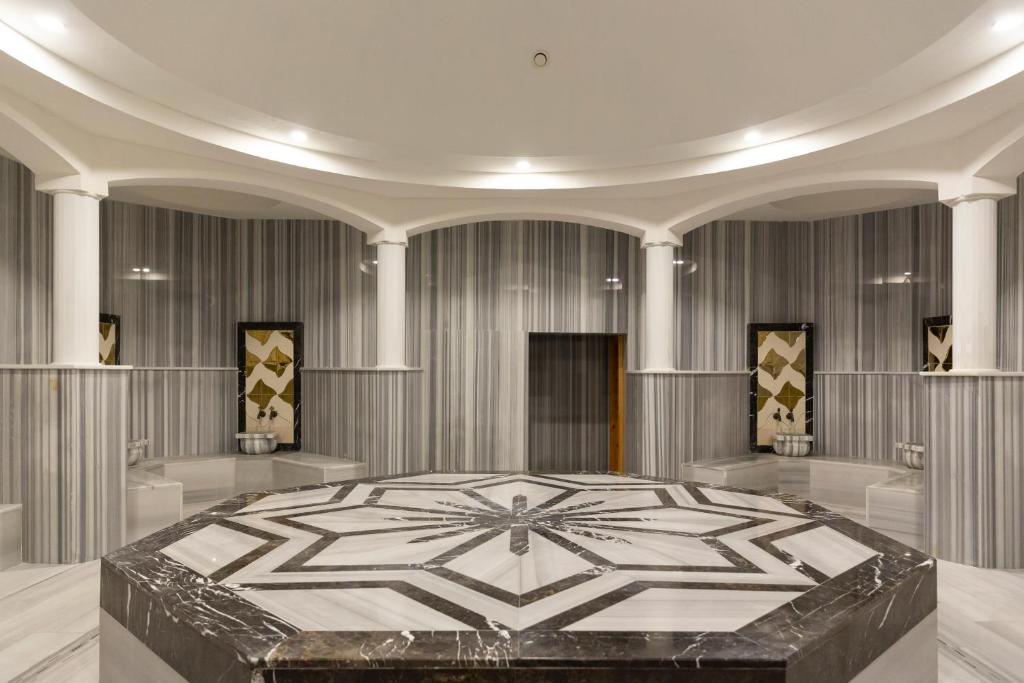 Marmora un akmens dizaina telpa ar elegantām kolonnām un ģeometrisku rakstu centrā. Šī mūsdienīgā un stilīgā vide ir ideāla relaksācijai un atpūtai.