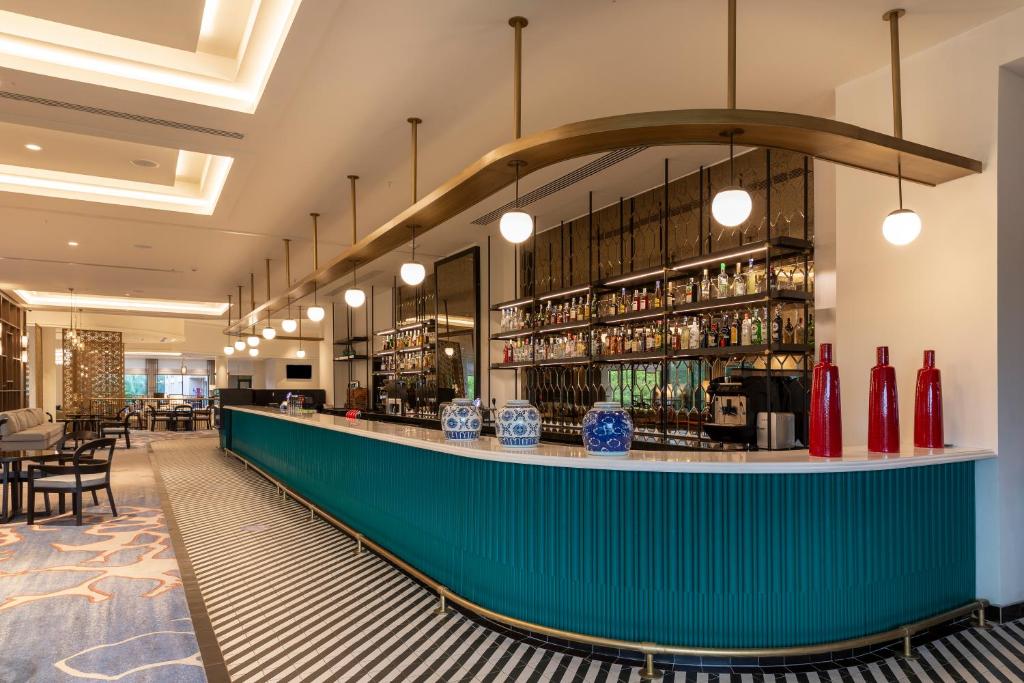 Moderns bārs ar zaļu letīti un elegantu interjeru, kas piedāvā plašu dzērienu izvēli. Gaisma un dizains rada patīkamu atmosfēru apmeklētājiem.