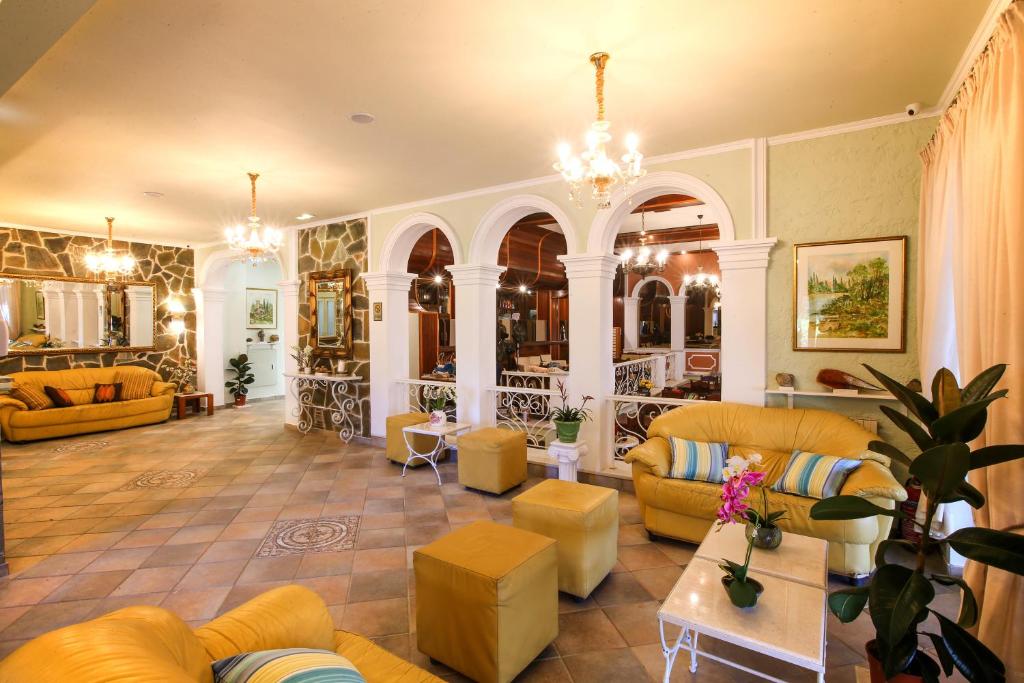 Elegants viesnīcas interjers ar dzeltenām mēbelēm un akmens sienām, kas rada mājīgu atmosfēru. Izsmalcināti gaismas ķermeņi un arhitektūras detaļas piešķir telpai šarmu.