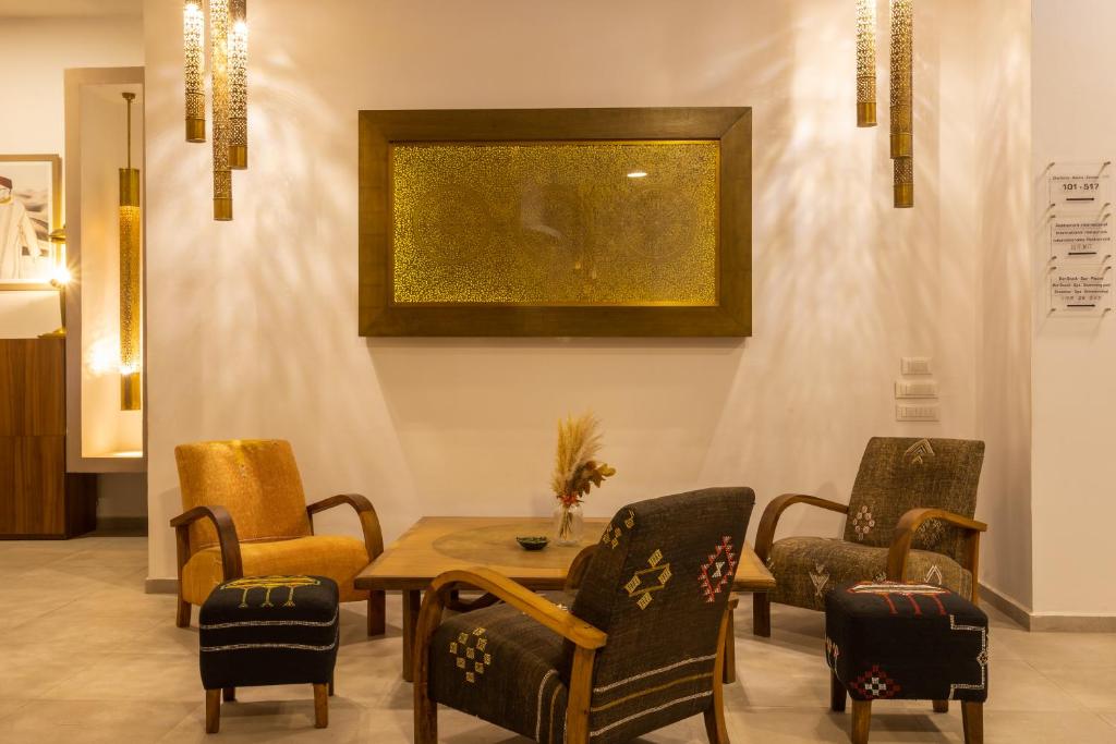 Mūsdienīgs viesnīcas interjers ar komfortablām krēslām un elegantu gaismas dizainu, radot siltu un viesmīlīgu atmosfēru. Izcils mākslas darbs pie sienas papildina telpas estētiku.