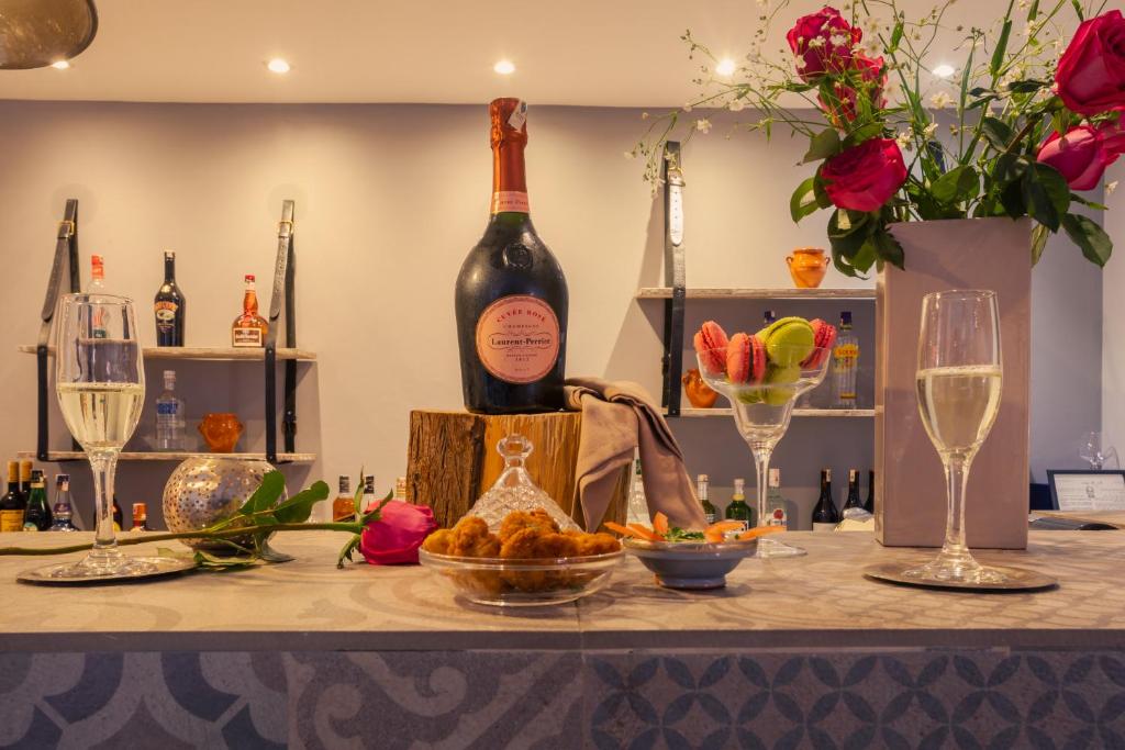 Elegantā galda kompozīcija ar šampanieti, desertiem un rozēm, radot svinīgu atmosfēru. Galda dekorācijas ietver glāzes, saldumus un ziedus, kas piešķir eleganci un romantiku.