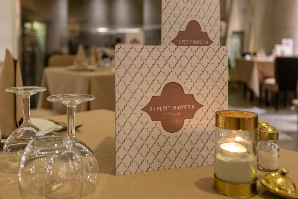 Restorāna "Au Petit Marocain" ēdienkarte uz galda ar elegantiem galda piederumiem un sveci, radot patīkamu atmosfēru.