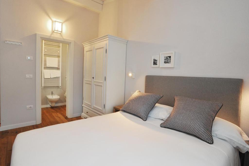 Mūsdienīga guļamistaba ar ērtu gultu, dekoratīvām spilveniem un piekļuvi vannas istabai. Svaiga krāsu palete un minimalistisks dizains rada relaksējošu atmosfēru.