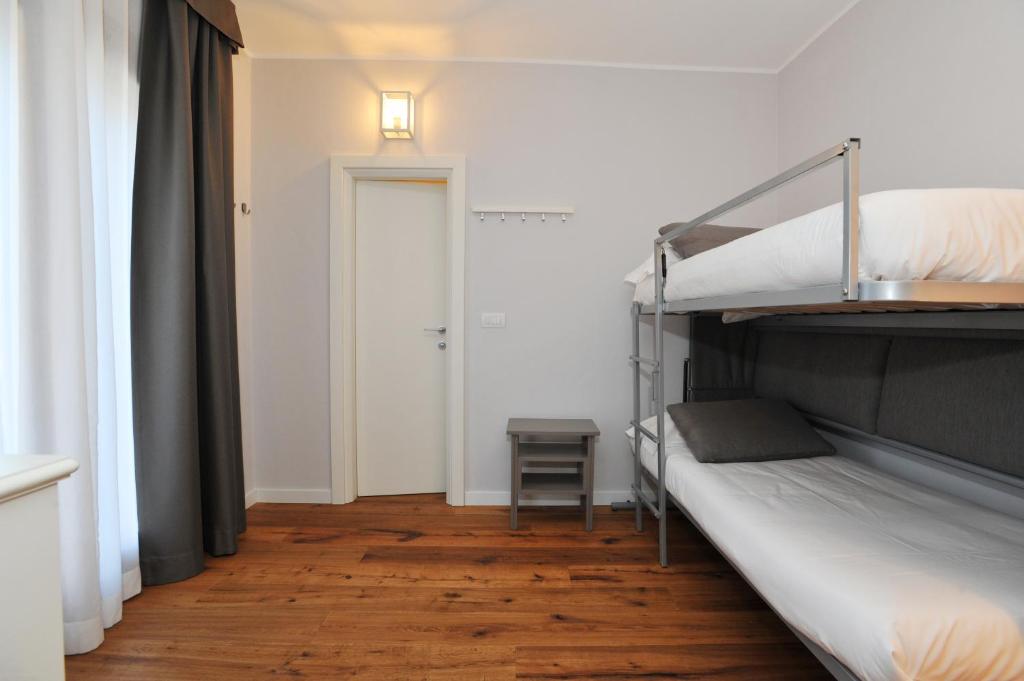 Moderns guļamistabas interjers ar divstāvu gultu, koka grīdu un dabiskiem apgaismojumiem. Telpa ir gaiša un vienkārša, ar minimālistisku dizainu.