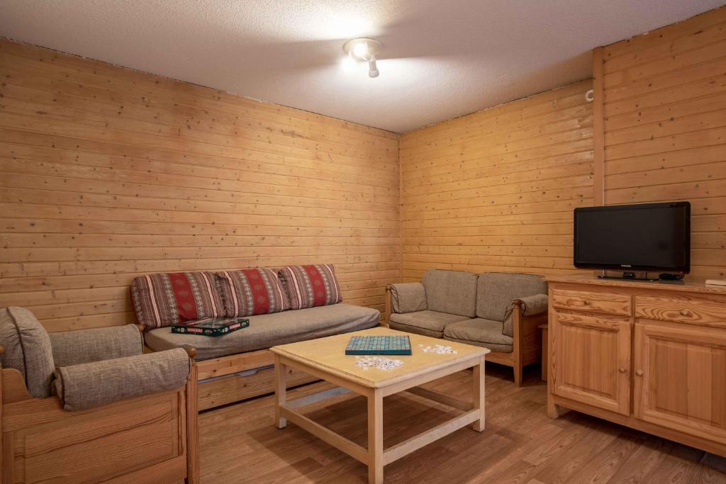 Mūsdienīga viesistaba ar koka sienām, diviem dīvāniem, kafijas galdiņu un televizoru, radot siltu un mājīgu atmosfēru. Ideāli piemērota relaksācijai un atpūtai.