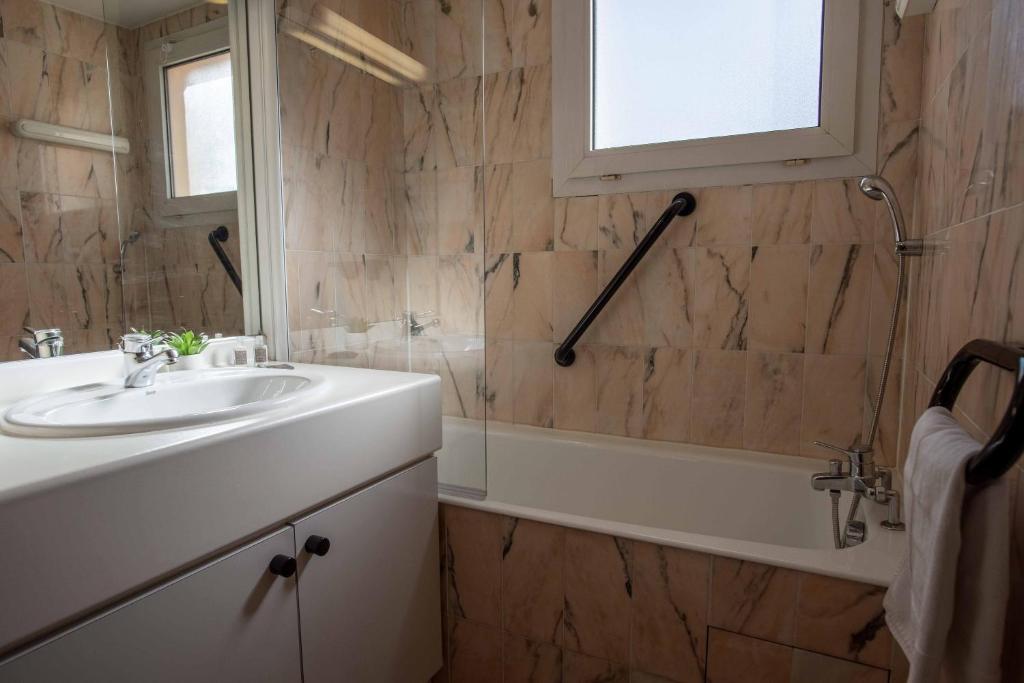 Mūsdienīgs vanna un izlietne vannas istabā ar marmora sienām, liela spogula un logu, kas nodrošina dabīgu apgaismojumu. 