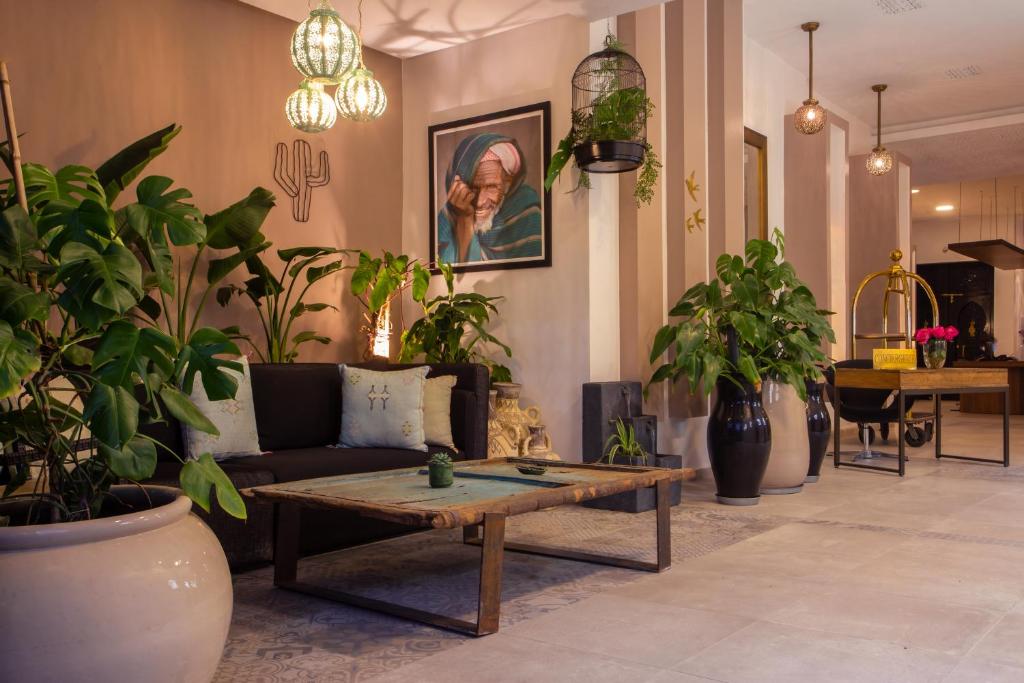 Mūsdienīgs interjers ar augiem un mākslas darbiem, kas rada patīkamu un relaksējošu atmosfēru. Dīvāns un koka galdiņš papildina telpas estētiku.