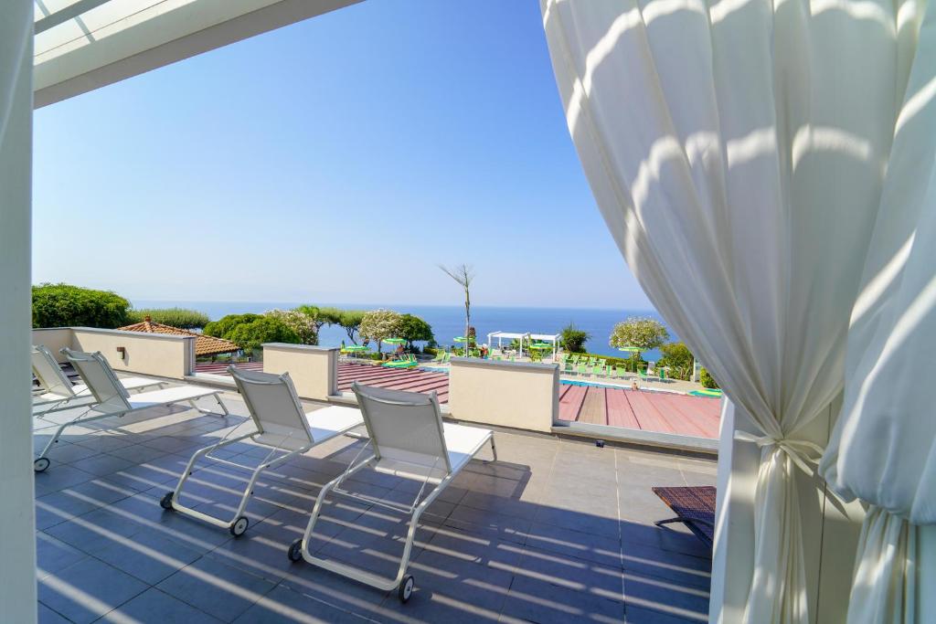 Terases skats uz jūru ar atpūtas krēsliem un zaļām ainavām. Gaisīga atmosfēra un brīnišķīgs laiks.