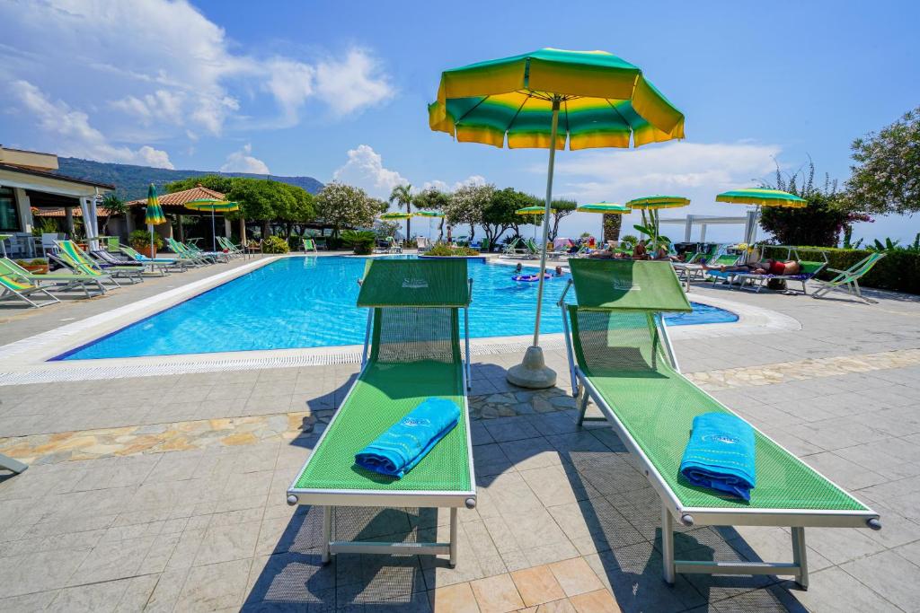 Peldbaseins ar zaļām sauļošanās krēslām un saulessargiem, apkārt ziedošas augu kompozīcijas un relaksējoša atmosfēra. Ideāla vieta atpūtai un saulainām dienām.