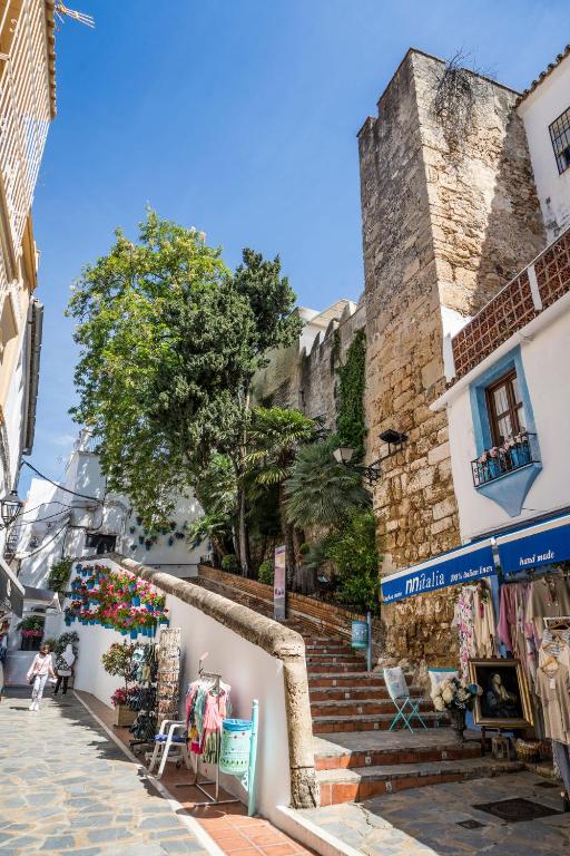 Šaura iela ar akmens kāpnēm, kas ved uz augšu, apzaļumota ar kokiem un ziediem, ar baltām mājām pa malām un veikaliem, kas piedāvā apģērbus un suvenīrus.