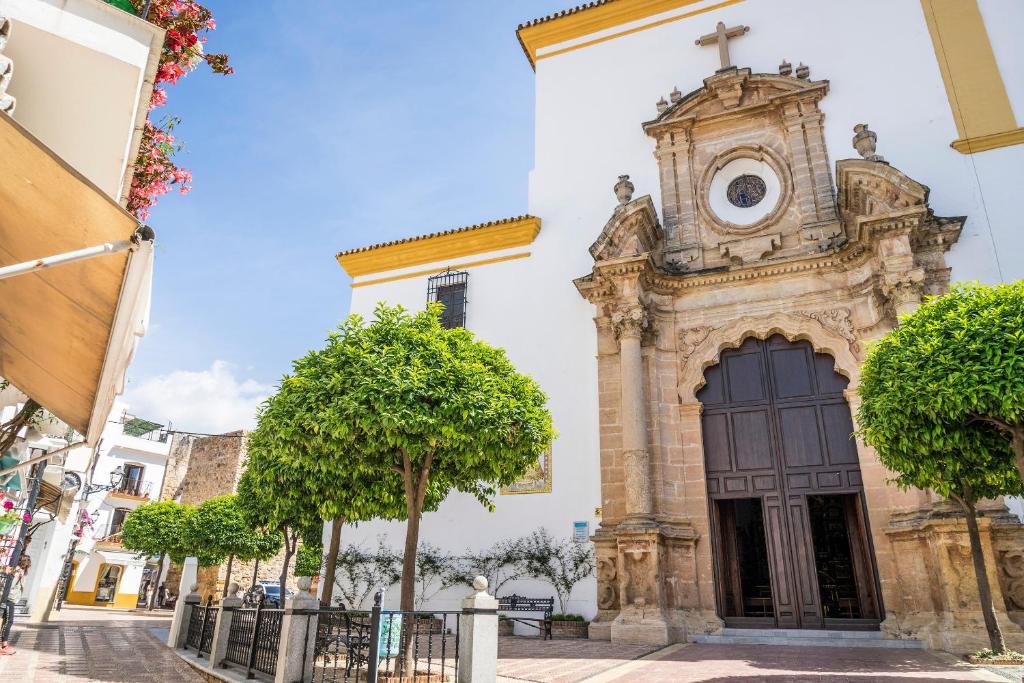 Vēsturiska baznīca ar izsmalcinātu arhitektūru un zaļiem kokiem priekšā, kas veido patīkamu atmosfēru. Ideāla vieta pastaigām un kultūras izpētei.